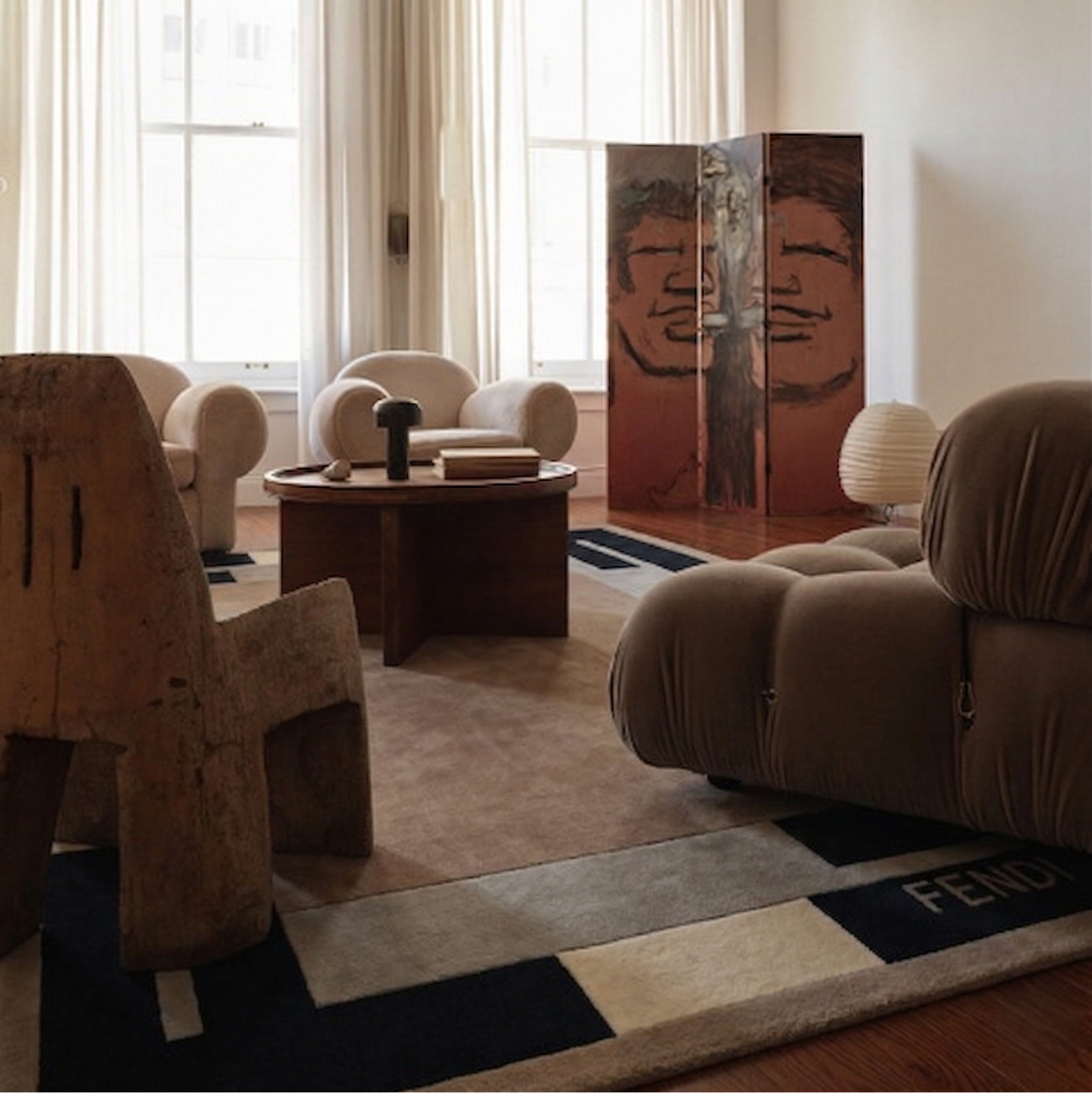 Modern living room with brown furniture, a rug, and a decorative screen.