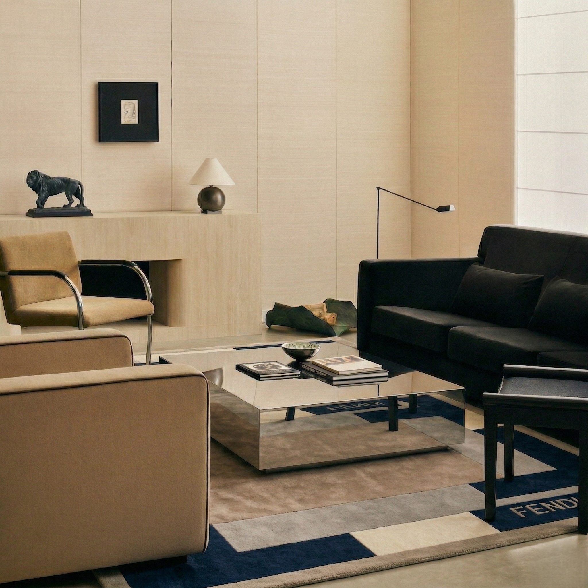 Modern living room with black sofa, beige armchair, and coffee table.