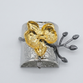 Silver and gold floral cuff bracelet on a light gray background