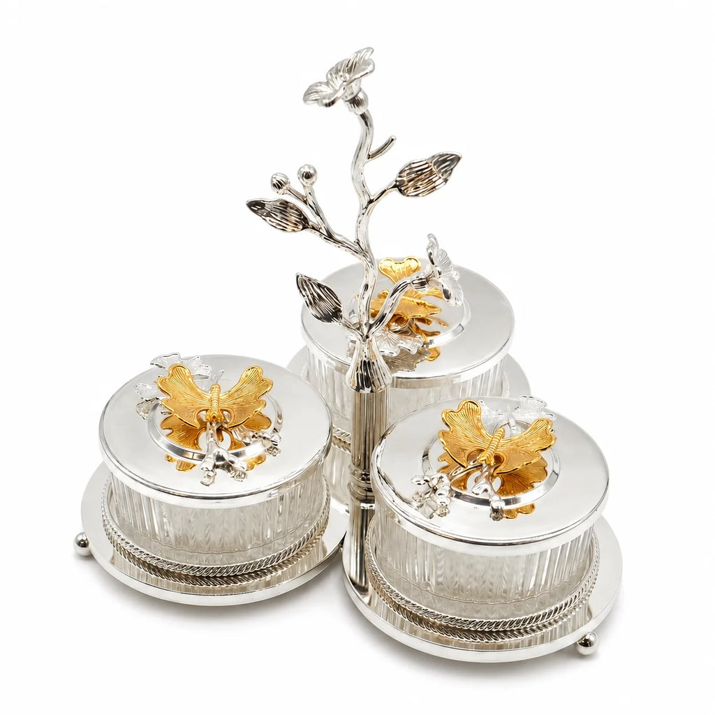 A three-piece silver and gold three-tiered serving set with ornate butterfly and floral details, photographed on a clean white background.