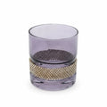 Purple glass tumbler with gold beaded band on a white background