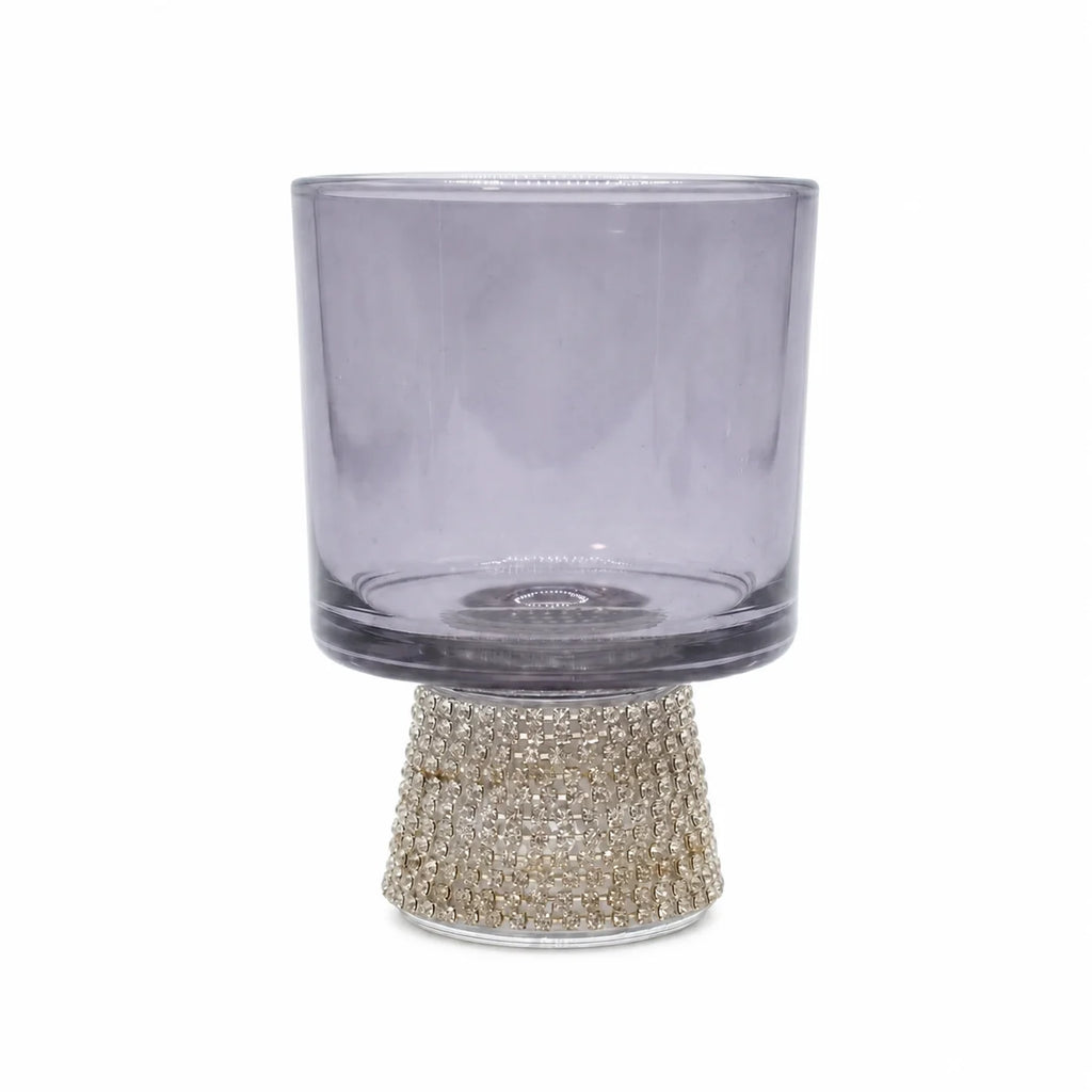 Clear glass candle holder with a decorative base on a white background