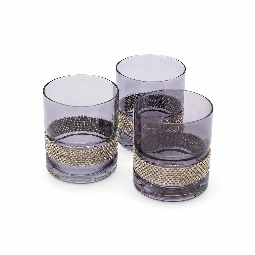 Three purple glass tumblers with gold mesh bands on a white background