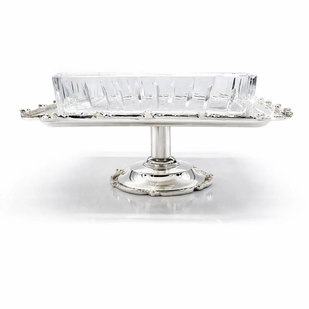 Clear glass dish on a silver stand with a white background