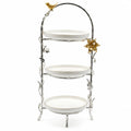 Three-tiered decorative stand with white plates and gold accents on a white background