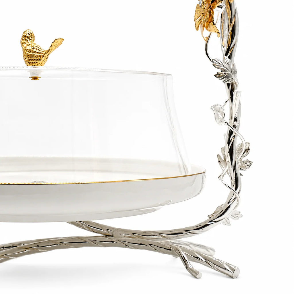 Decorative glass dish with gold bird and silver leaf design on a white background